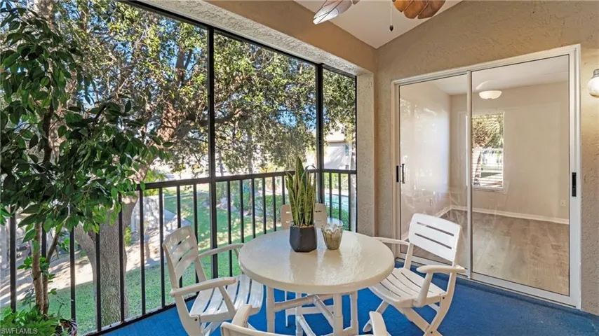 Sunroom with a textured wall, ceiling fan, wood finished floors, and a balcony