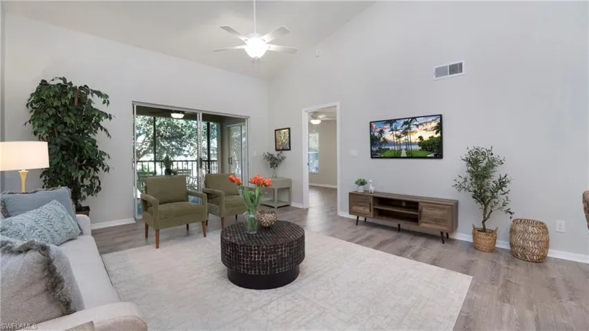 Living room with light wood-style floors, high vaulted ceiling, and ceiling fan