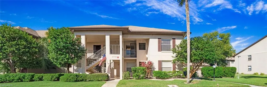 View of front of property with a front lawn, stucco siding, and stairs