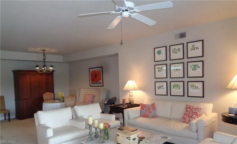 Living area featuring a chandelier, ceiling fan, and carpet flooring