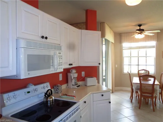 Kitchen featuring white appliances, ceiling fan, and white cabinetry
