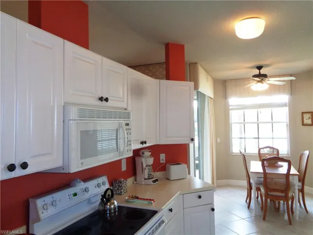 Kitchen with white appliances, a ceiling fan, white cabinets, and light countertops
