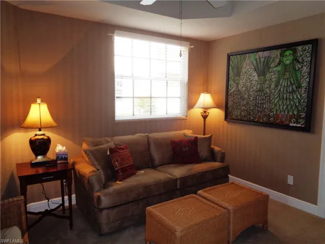 Living area with carpet, plenty of natural light, and ceiling fan