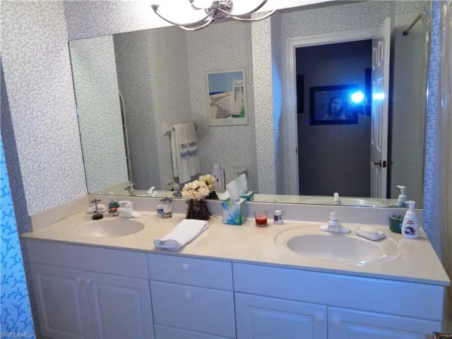 Bathroom featuring wallpapered walls and double vanity