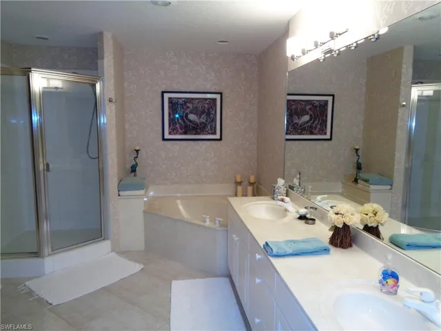 Full bath with wallpapered walls, double vanity, a bath, a shower stall, and tile patterned floors