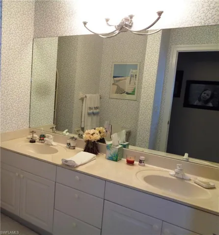 Full bath with wallpapered walls, double vanity, and a chandelier