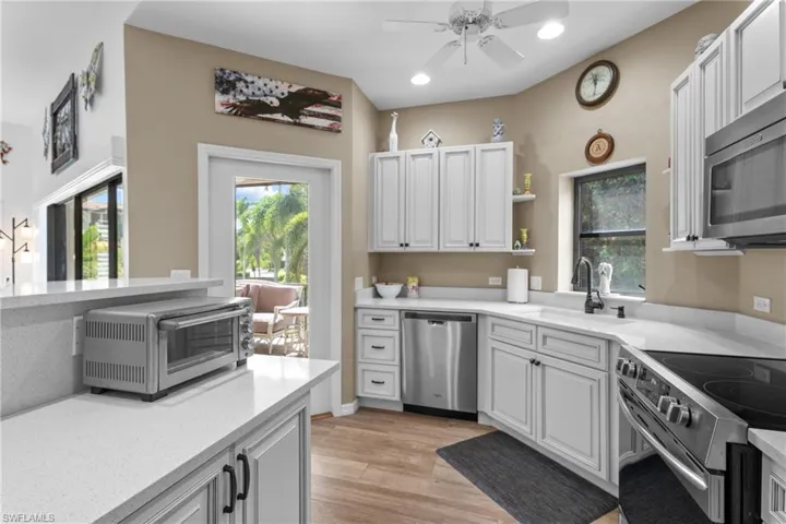 Kitchen featuring white cabinets, sink, ceiling fan, light wood-type flooring, and stainless steel appliances