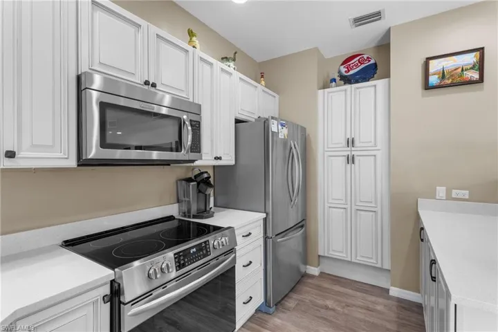 Kitchen with white cabinets, light wood-type flooring, and appliances with stainless steel finishes