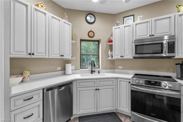 Kitchen with stainless steel appliances, white cabinetry, hardwood / wood-style flooring, and sink