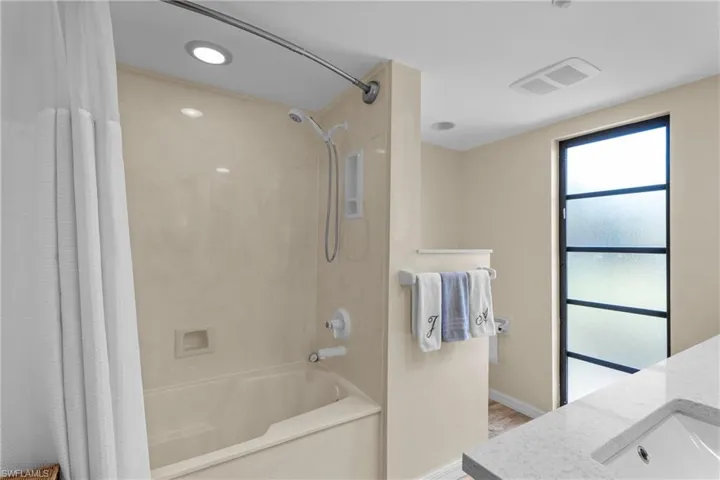 Bathroom featuring vanity, hardwood / wood-style floors, and shower / bathtub combination with curtain