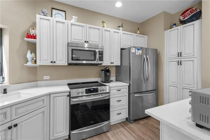 Kitchen with white cabinets, light wood-type flooring, stainless steel appliances, and sink