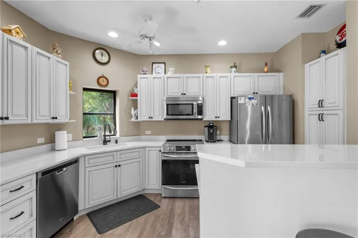 Kitchen featuring stainless steel appliances, ceiling fan, sink, light hardwood / wood-style flooring, and white cabinets