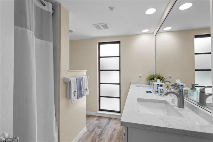 Bathroom with curtained shower, hardwood / wood-style floors, and vanity