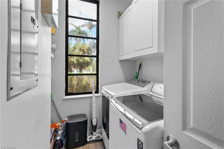 Laundry room with washing machine and dryer, cabinets, and wood-type flooring