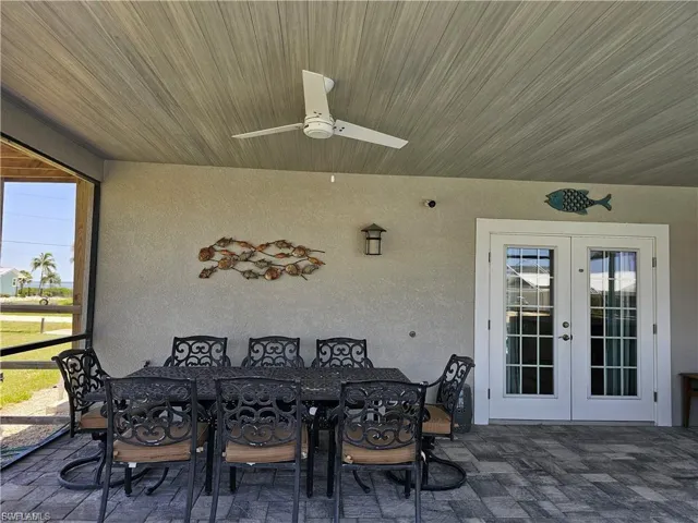 View of patio featuring outdoor dining area, ceiling fan, a sunroom, and french doors