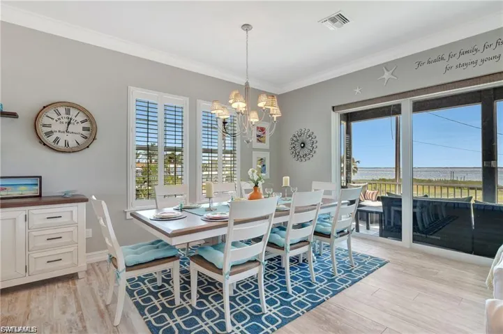 Dining space featuring crown molding, light wood finished floors, plenty of natural light, and a chandelier