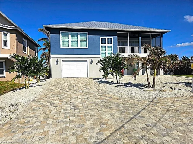 View of front of property with a metal roof, decorative driveway, stucco siding, a garage, and a sunroom