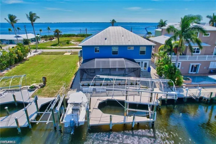 Rear view of house with a water view, boat lift, and a lanai
