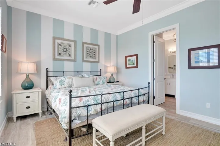 Bedroom featuring light wood-style flooring, ceiling fan, ornamental molding, and ensuite bath