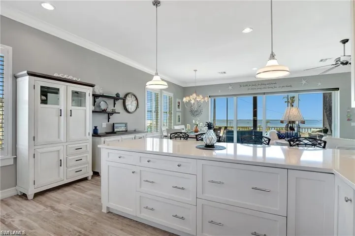 Kitchen with white cabinetry, hanging light fixtures, light stone counters, light wood-style floors, and open shelves