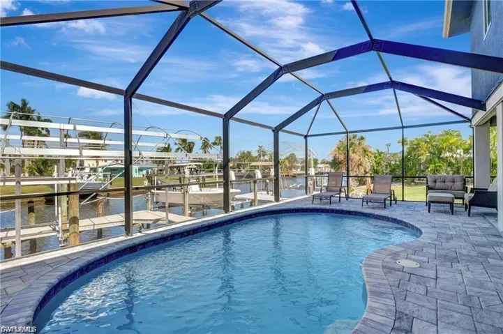 Swimming pool featuring boat lift, a sunroom, a dock, a water view, and a lanai