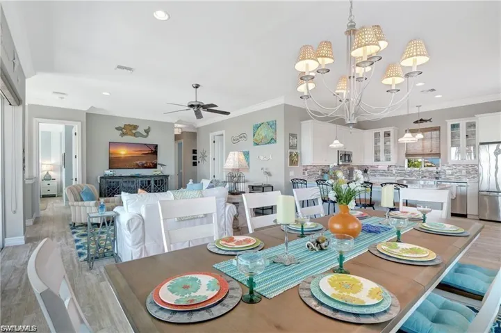 Dining area with light wood-style floors, crown molding, a chandelier, recessed lighting, and ceiling fan
