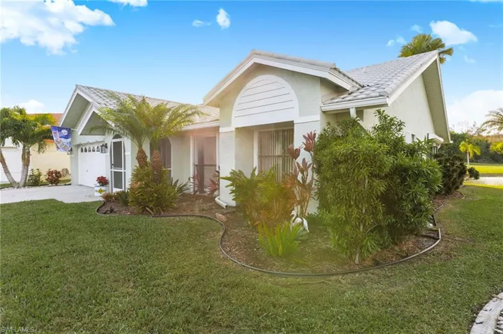 Single story home featuring a front yard, driveway, stucco siding, a garage, and a tiled roof