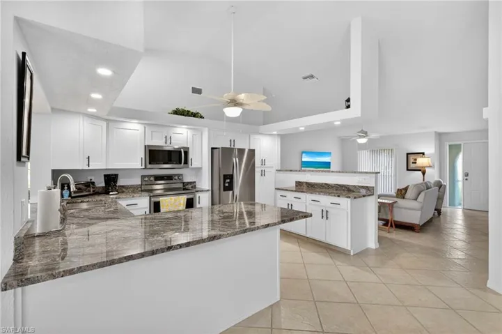 Kitchen with a peninsula, recessed lighting, open floor plan, dark stone countertops, and white cabinets