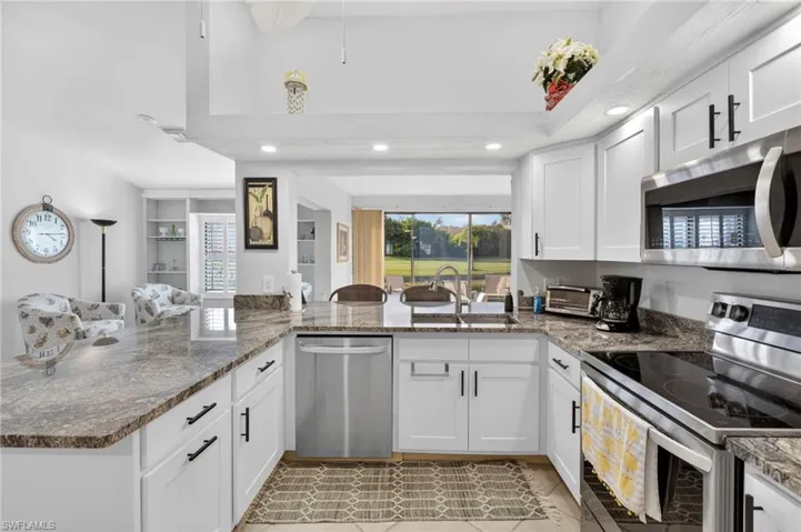 Kitchen featuring a peninsula, stainless steel appliances, white cabinets, open floor plan, and recessed lighting