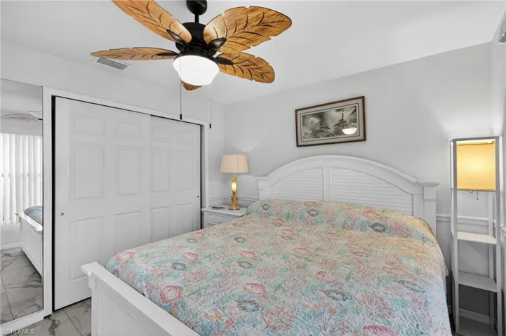 Bedroom with marble look tiles, a ceiling fan, and a closet