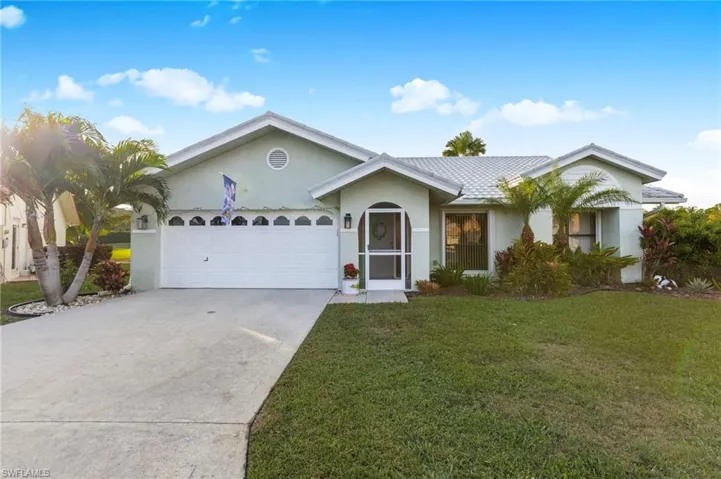 Ranch-style home featuring driveway, a front lawn, stucco siding, and an attached garage