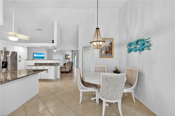 Dining space with light tile patterned floors, a high ceiling, a chandelier, and a ceiling fan