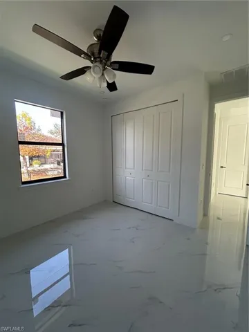 Unfurnished bedroom featuring marble look tiles, a closet, and ceiling fan