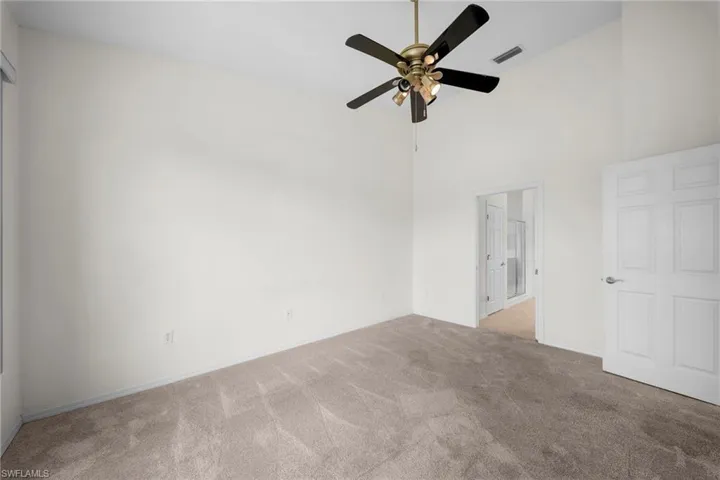 Vaulted ceiling room featuring neutral-toned carpeting and a ceiling fan with integrated lighting