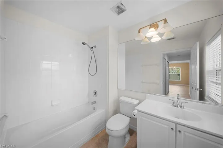 Bathroom featuring a white vanity with integrated sink, chrome faucet, and a large wall-mounted mirror