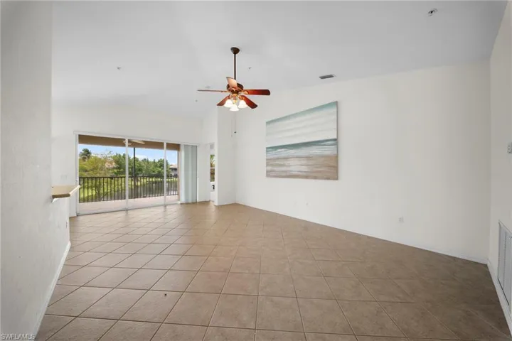 Spacious interior featuring tile flooring, vaulted ceilings, and a ceiling fan with integrated lighting