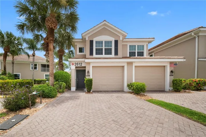 Two-story stucco residence featuring a two-car garage, dark entry door, and second-story dormer