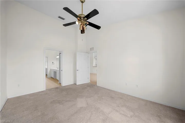 Carpeted room featuring a vaulted ceiling and a ceiling fan with integrated lighting