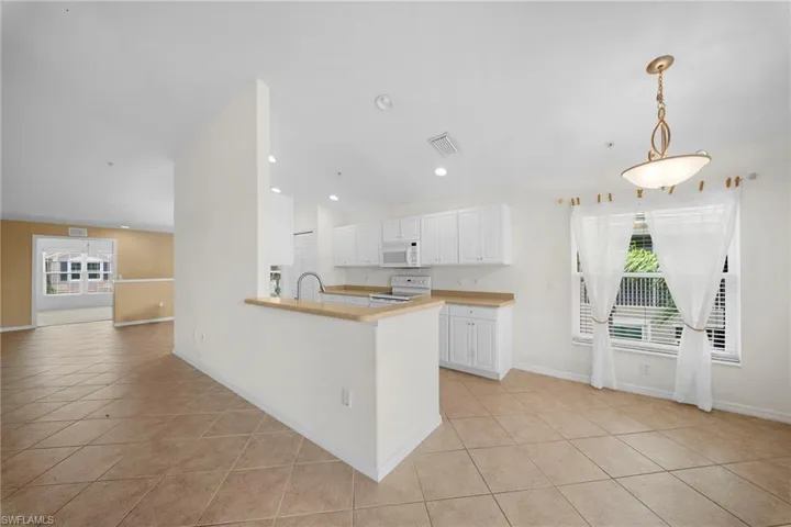 Kitchen and dining area featuring white cabinetry, light wood-finish countertops, stainless steel appliances, and a double basin sink