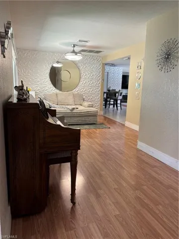 Living room featuring a textured wall, wood finished floors, and wallpapered walls
