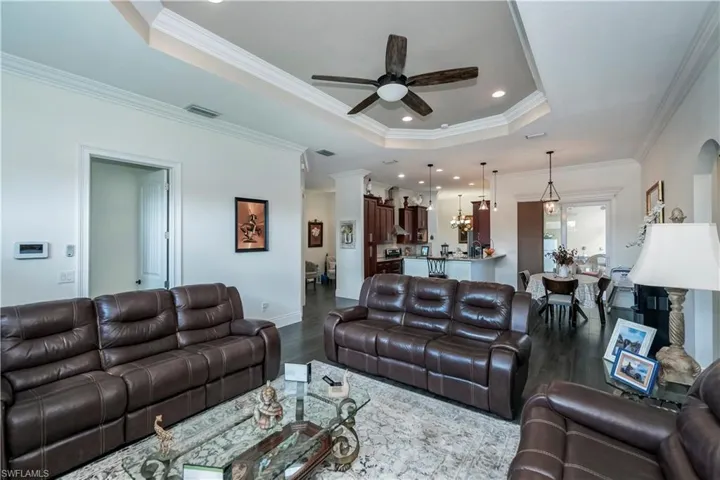 Living room featuring crown molding, a tray ceiling, ceiling fan, and hardwood / wood-style flooring