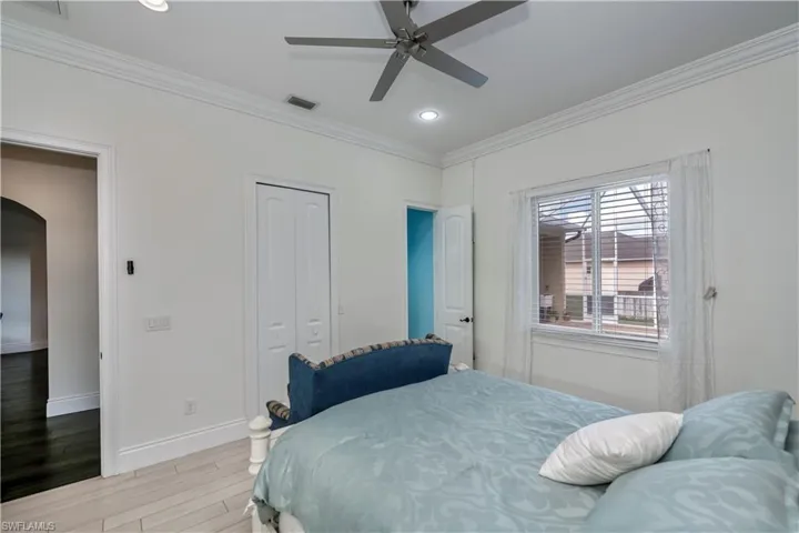 Bedroom featuring crown molding, light hardwood / wood-style flooring, a closet, and ceiling fan