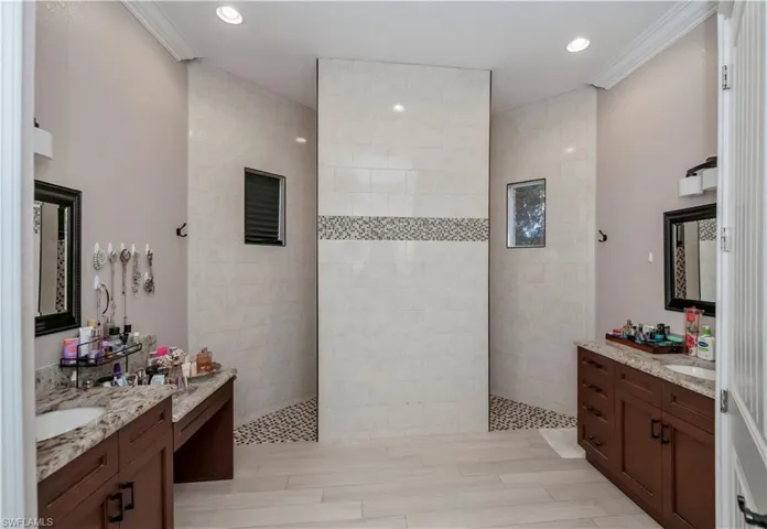 Bathroom featuring tiled shower, vanity, and ornamental molding