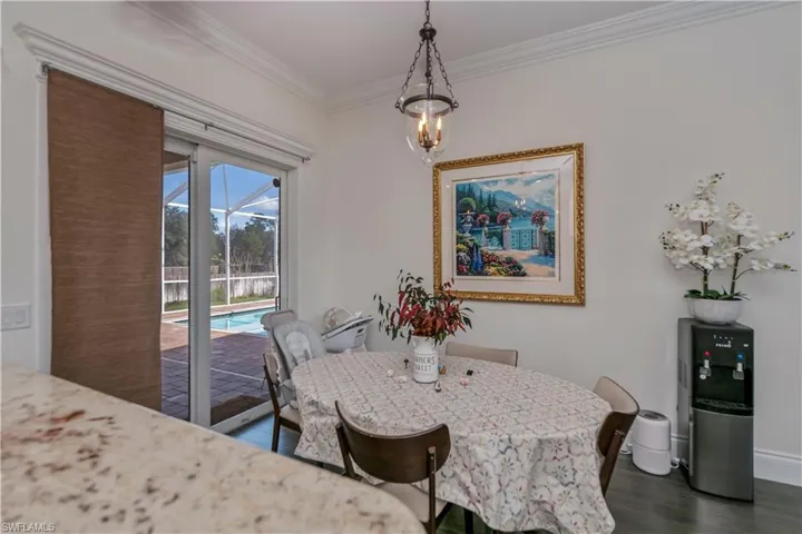 Breakfast space with crown molding, dark hardwood / wood-style floors, and an inviting chandelier