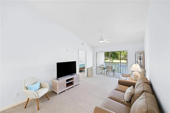 Living area with light carpet, lofted ceiling, and a ceiling fan