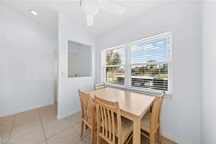 Dining area featuring vaulted ceiling, light tile patterned floors, and a ceiling fan