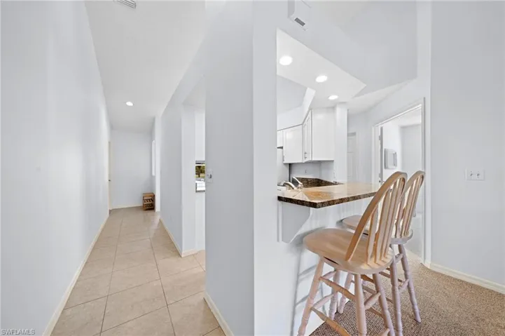 Kitchen featuring white cabinetry, a kitchen breakfast bar, a peninsula, recessed lighting, and light tile patterned flooring