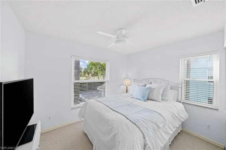Bedroom with light colored carpet, a textured ceiling, and ceiling fan