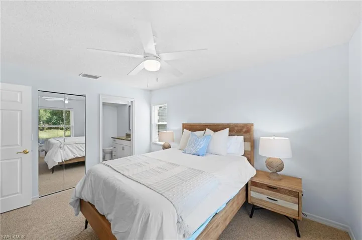 Carpeted bedroom featuring ensuite bathroom, ceiling fan, a textured ceiling, and a closet