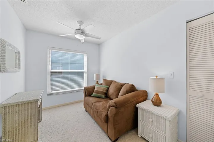 Living room featuring ceiling fan, light colored carpet, and a textured ceiling